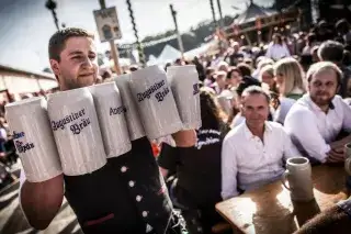 201216_wiesn-bedienung-gaeste_exithamster Bedienung trägt Steinkrüge mit Bier auf der Oidn Wiesn