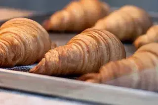 210128_croissants-auf-backblech Frisch gebackene Croissants auf einem Backblech.