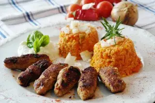 Ein Teller mit Cevapcici-Fleischröllchen und Reis Ein Teller mit sechs Cevapcici-Fleischröllchen und Reis