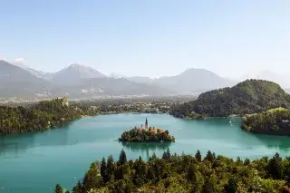 Slowenien: See bei Bled Panorama des Sees Bled in Slowenien mit kristallklarem Wasser bei blauem Himmel und Wäldern am Ufer