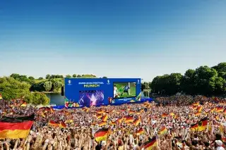 Visualisierung der Fan Zone im Olympiapark Visualisierung der Fan Zone im Olympiapark: Deutsches Publikum mit Fahnen vor Großbild-Leinwand bei Sonnenschein