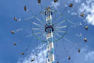 Kettenflieger Bayern Tower mit Fahrgästen vor blau-weißem Himmel 
