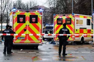 Rettungskräfte stehen in der Nähe des Einsatzortes. In München ist ein Fahrzeug in eine Menschengruppe gefahren.